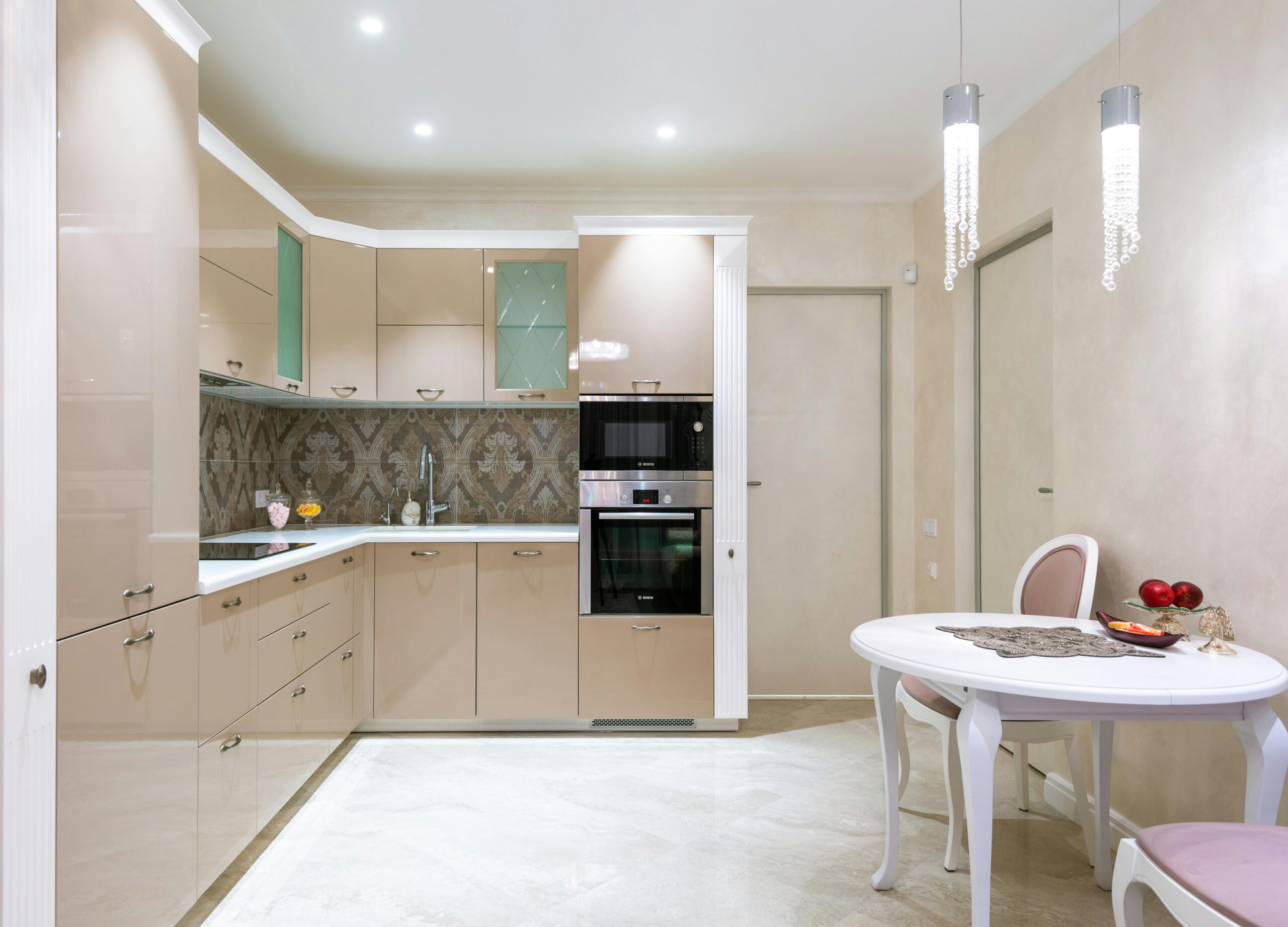 Sleek and modern beige kitchen interior featuring cozy dining table and contemporary appliances.