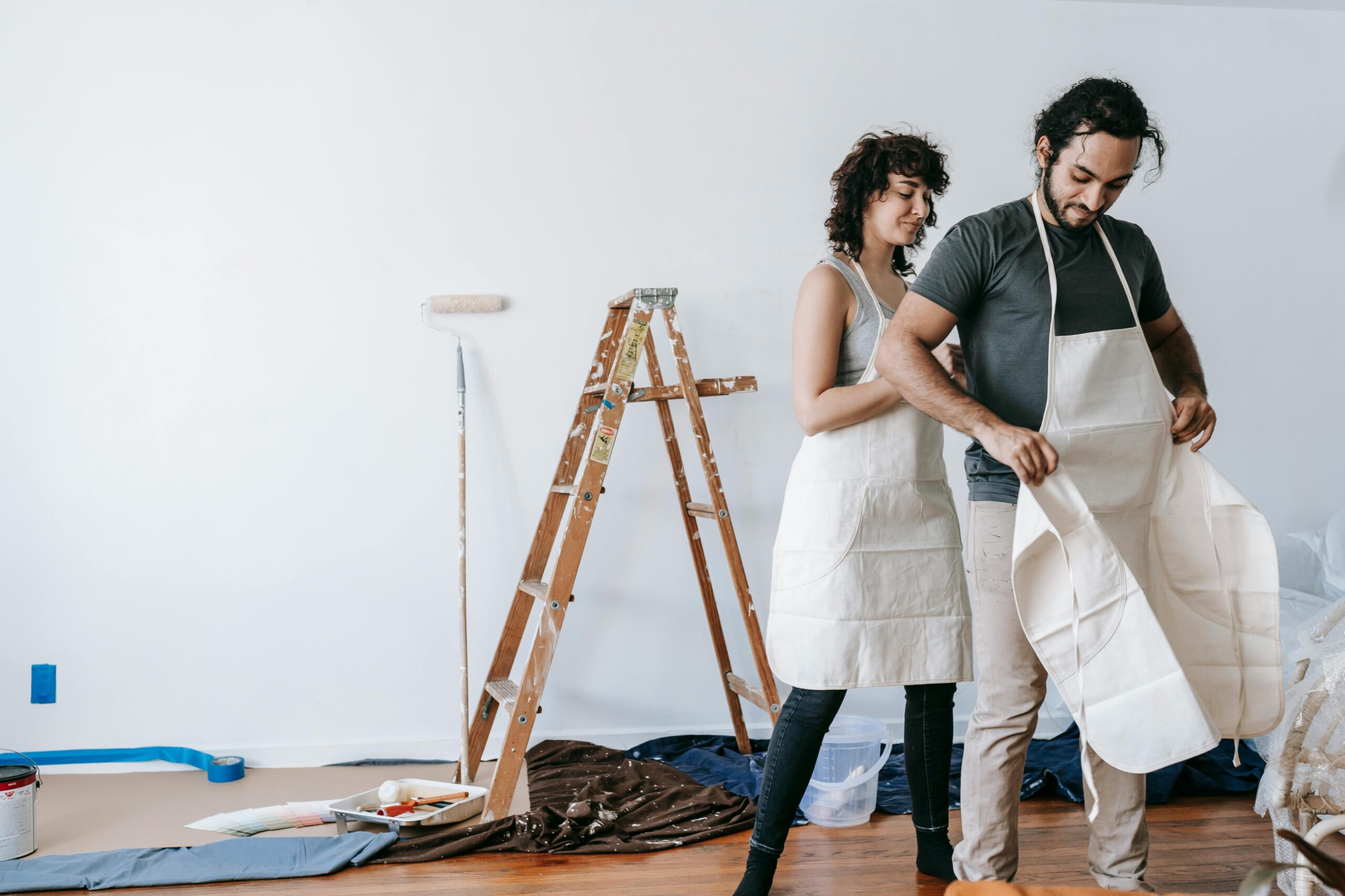 A couple in aprons getting ready to renovate their home, showing teamwork and joy.